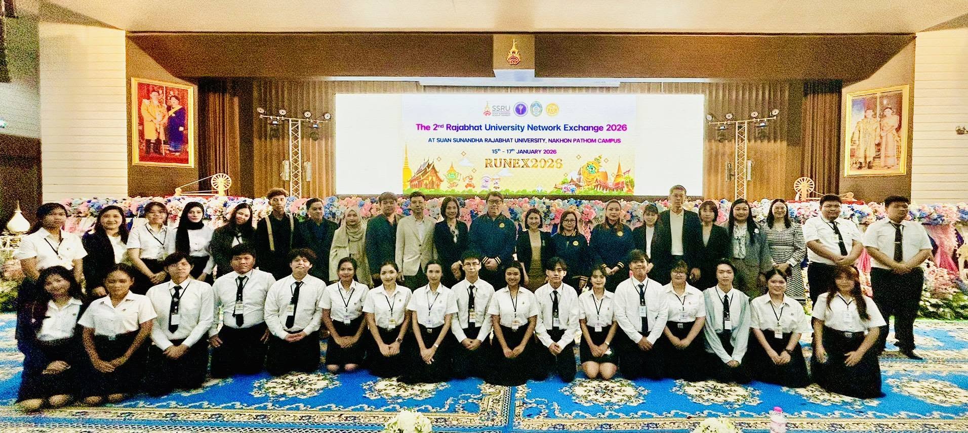 Official group photograph of students and faculty on a decorated university stage