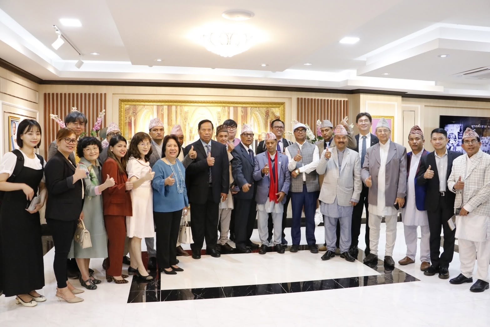 Delegation including guests in Nepali traditional dress posing with university officials in a lobby